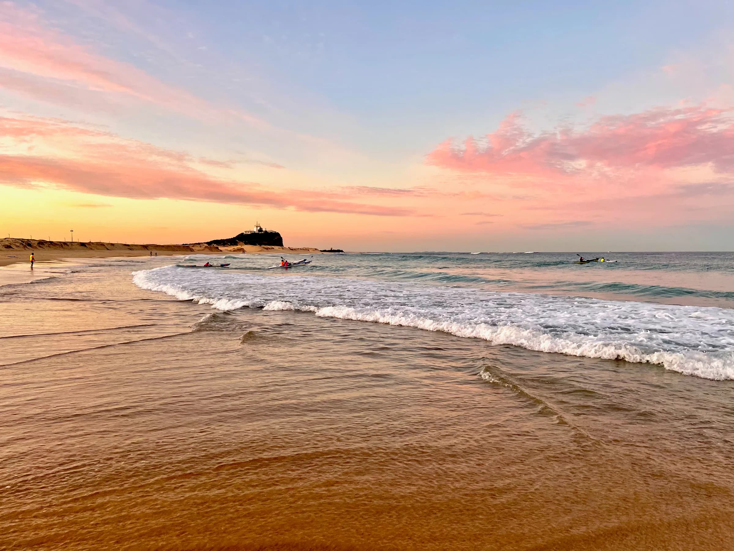 Waves at Nobbys Beach in Newcastle beneath a pink sky